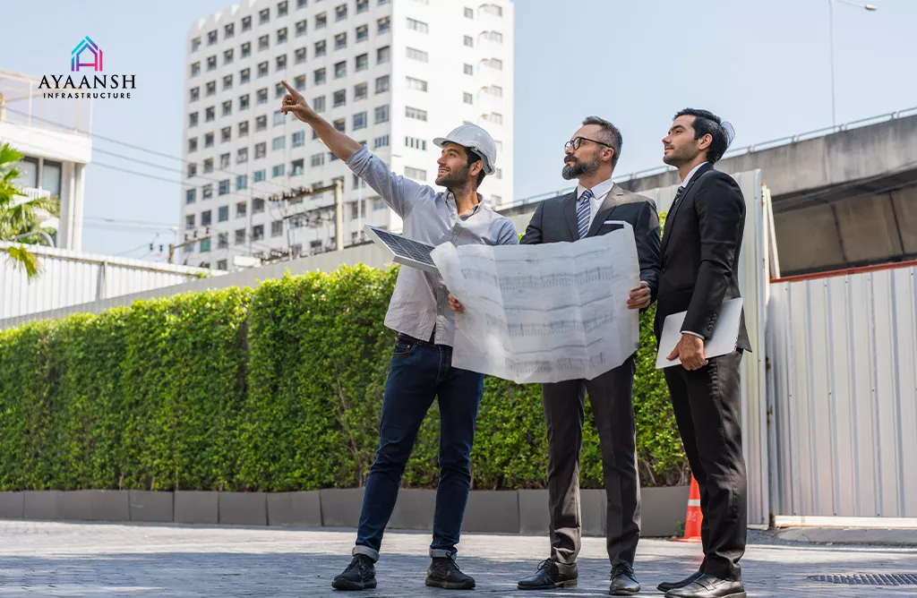  Professional Builders In Vizag Reviewing Architectural Plans At Construction Site 